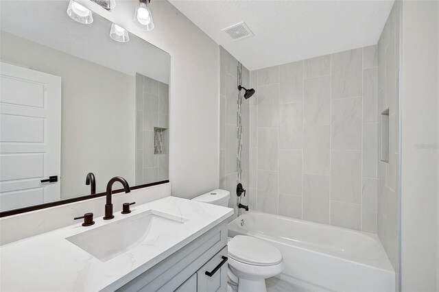 full bathroom with vanity, tiled shower / bath combo, and toilet