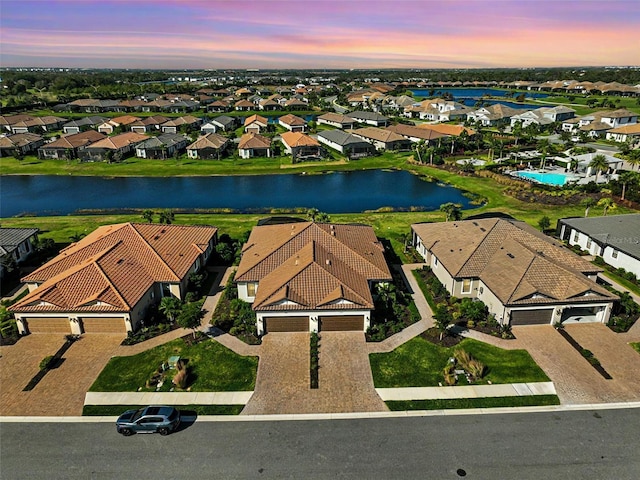 aerial view at dusk featuring a water view