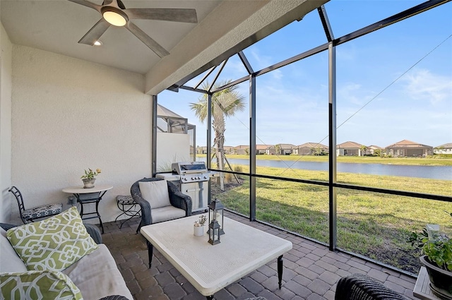 sunroom / solarium with a wealth of natural light, ceiling fan, and a water view