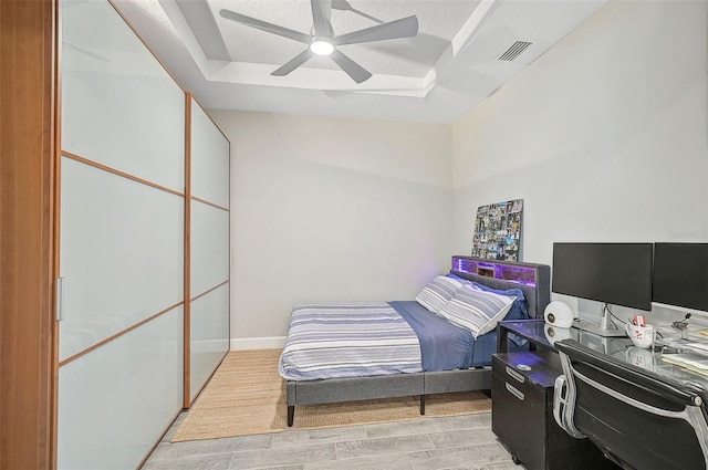 bedroom featuring a raised ceiling, ceiling fan, and light hardwood / wood-style floors