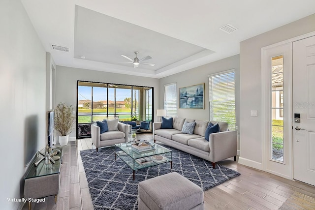 living room featuring a tray ceiling and ceiling fan