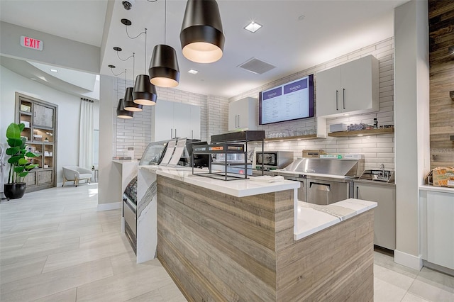 kitchen featuring decorative backsplash, light tile patterned floors, and decorative light fixtures