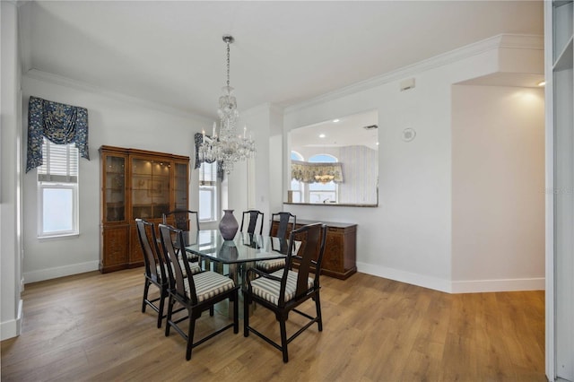 dining space with an inviting chandelier, light hardwood / wood-style flooring, and crown molding