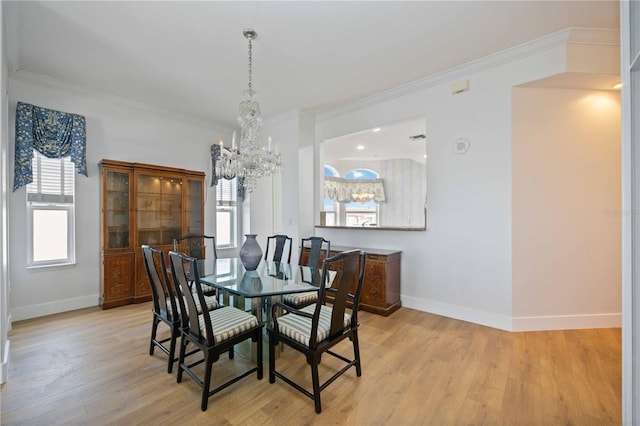 dining area with light wood-type flooring, ornamental molding, and a notable chandelier