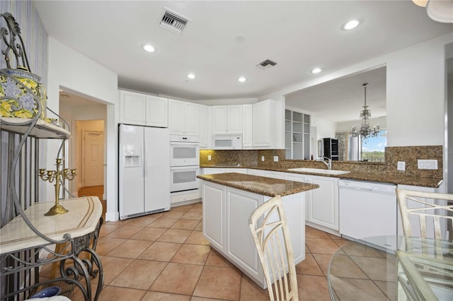 kitchen with dark stone countertops, sink, white appliances, and kitchen peninsula