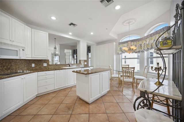 kitchen with pendant lighting, white cabinets, sink, light tile patterned flooring, and electric stovetop