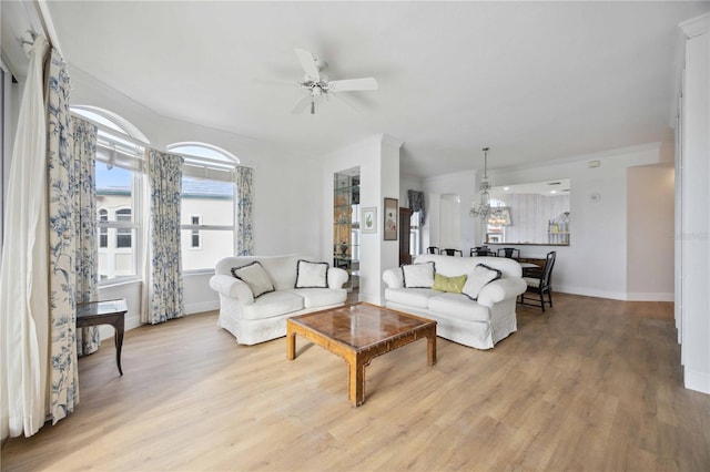 living room featuring ceiling fan with notable chandelier and light hardwood / wood-style floors