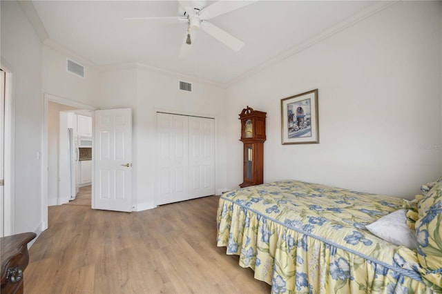 bedroom featuring ceiling fan, crown molding, light hardwood / wood-style flooring, and a closet