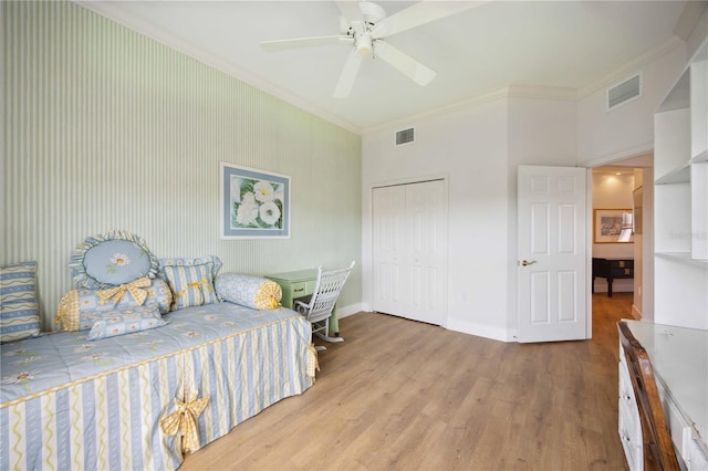 bedroom featuring ceiling fan, light wood-type flooring, crown molding, and a closet