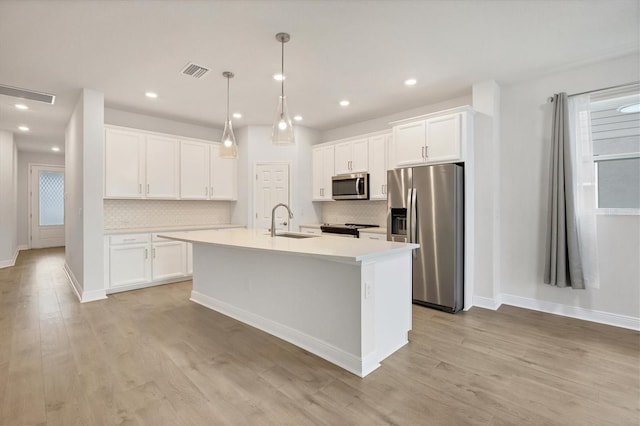 kitchen featuring sink, stainless steel appliances, an island with sink, light hardwood / wood-style floors, and white cabinets