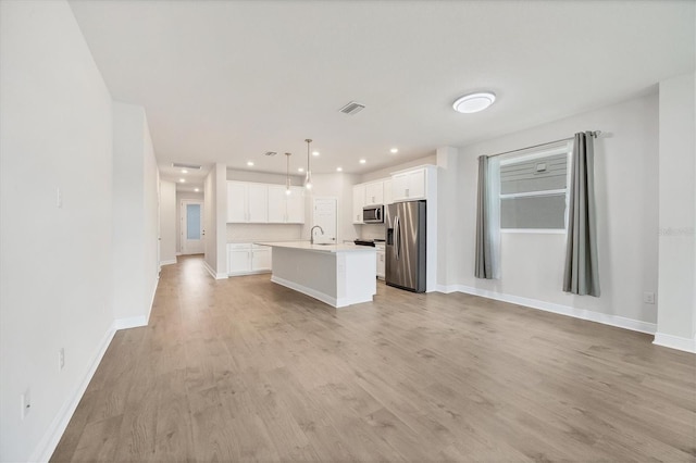 kitchen with a center island with sink, light hardwood / wood-style flooring, decorative light fixtures, white cabinetry, and stainless steel appliances