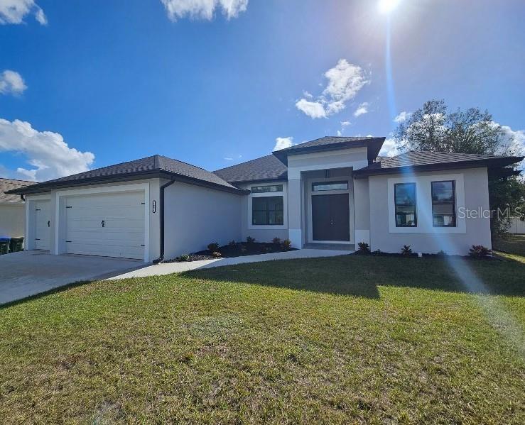 prairie-style house with a garage, driveway, a front lawn, and stucco siding