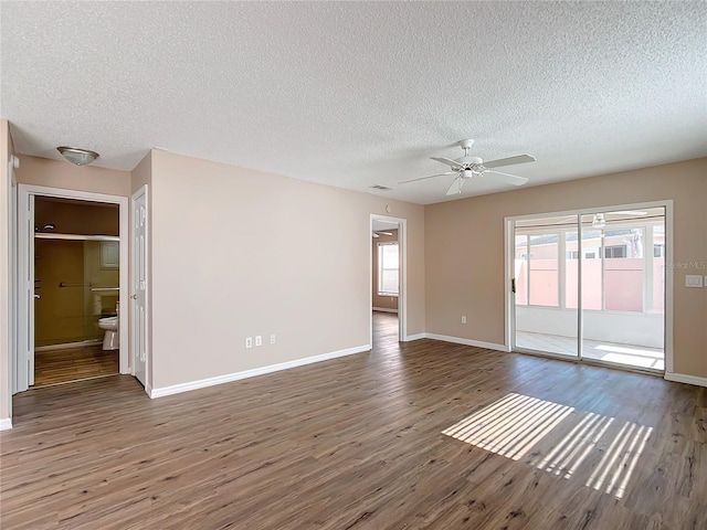 unfurnished room featuring dark wood-type flooring, a wealth of natural light, a textured ceiling, and ceiling fan