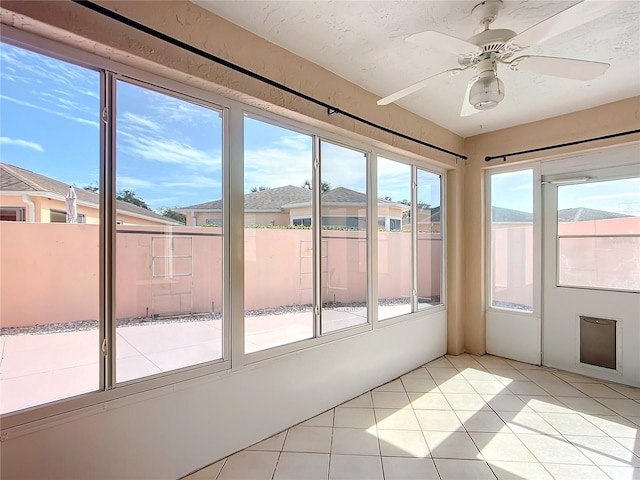 doorway with ceiling fan and light tile patterned flooring