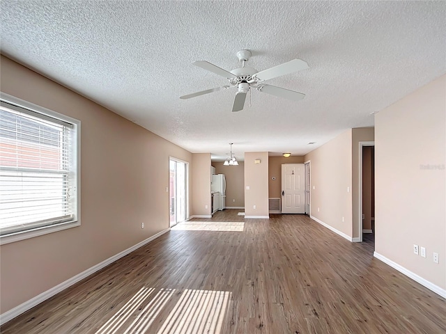 unfurnished living room with hardwood / wood-style flooring, plenty of natural light, a textured ceiling, and ceiling fan with notable chandelier