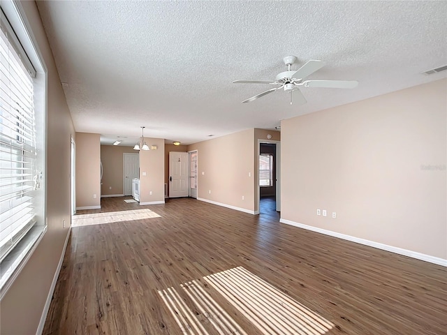 unfurnished living room with dark wood-type flooring, ceiling fan with notable chandelier, and a textured ceiling