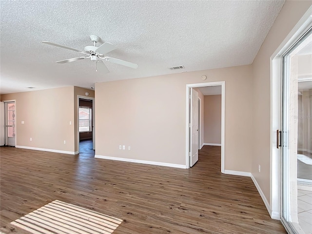 empty room with a textured ceiling, dark hardwood / wood-style floors, and ceiling fan