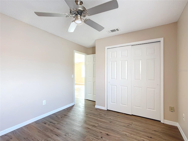 unfurnished bedroom with hardwood / wood-style floors, a closet, and ceiling fan