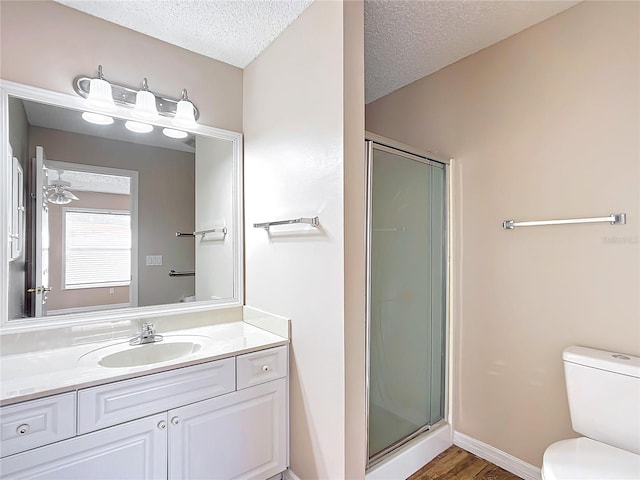 bathroom with hardwood / wood-style flooring, vanity, toilet, a shower with door, and a textured ceiling