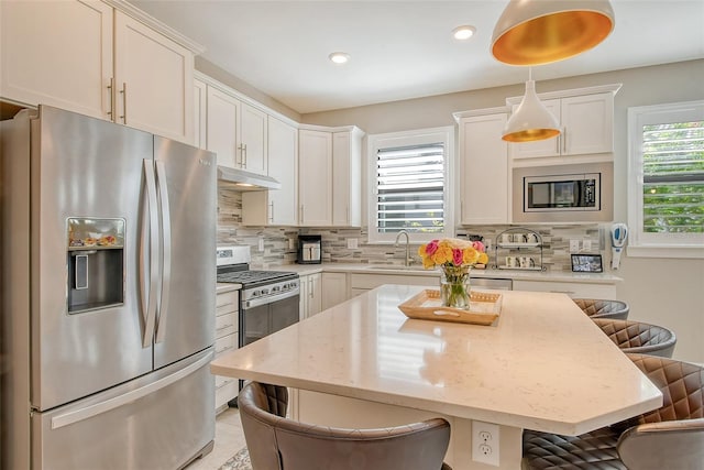 kitchen with plenty of natural light, a breakfast bar, stainless steel appliances, and decorative light fixtures