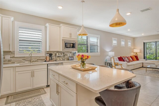 kitchen featuring pendant lighting, a center island, a healthy amount of sunlight, and sink