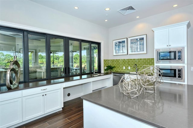 kitchen featuring white cabinets, decorative backsplash, stainless steel appliances, and dark hardwood / wood-style floors