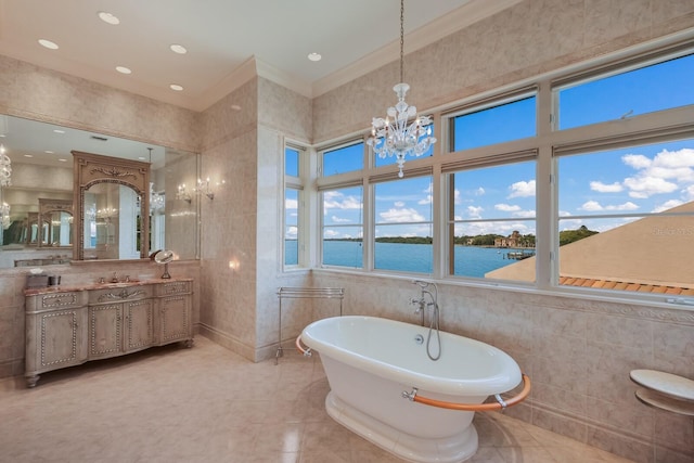 bathroom featuring crown molding, a water view, a bathtub, vanity, and tile walls