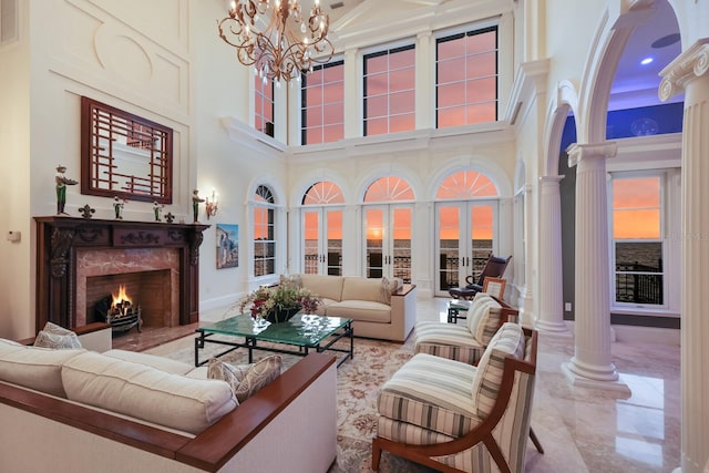 living room featuring a towering ceiling, a high end fireplace, and ornate columns