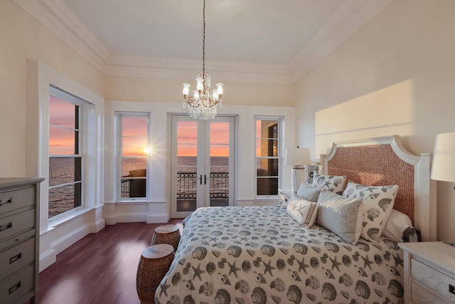 bedroom featuring an inviting chandelier, dark hardwood / wood-style floors, access to outside, a water view, and ornamental molding