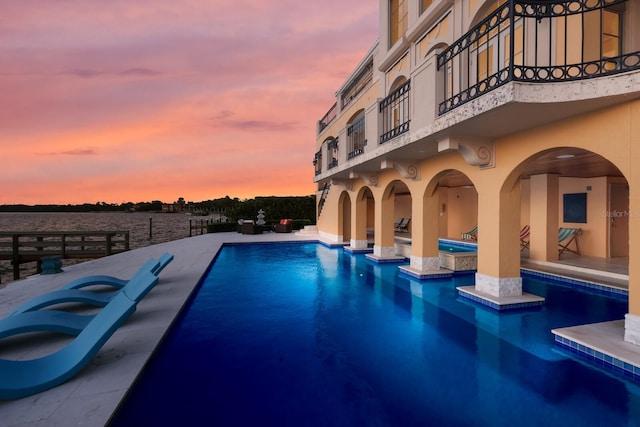 pool at dusk featuring a patio