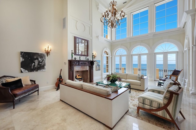 living room featuring a water view, french doors, a high ceiling, and an inviting chandelier