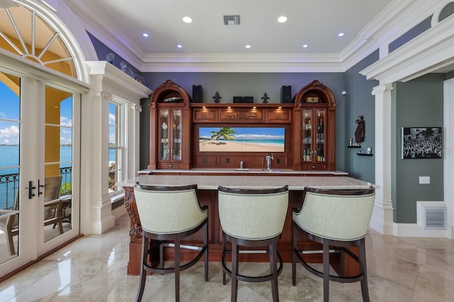 bar with crown molding, french doors, and a water view