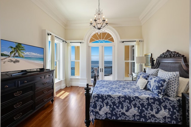 bedroom featuring access to exterior, a water view, multiple windows, and hardwood / wood-style flooring