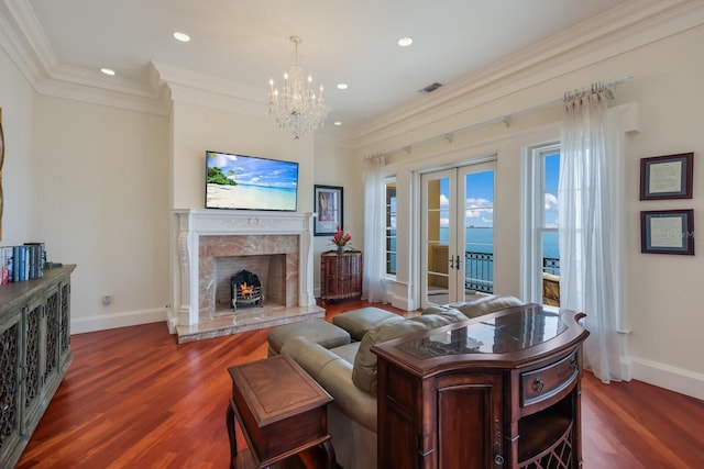 living room featuring french doors, dark hardwood / wood-style flooring, ornamental molding, and a premium fireplace