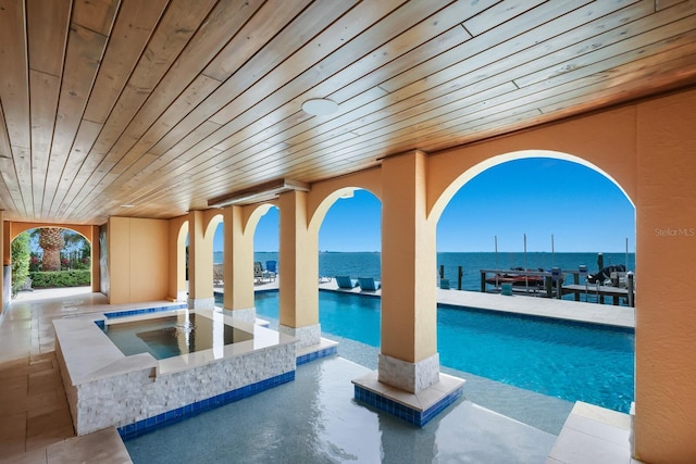 view of pool with a jacuzzi and a water view