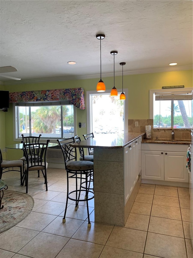 kitchen with a kitchen breakfast bar, white cabinets, kitchen peninsula, pendant lighting, and light tile patterned flooring