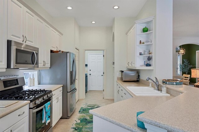 kitchen with stainless steel appliances, sink, light tile patterned floors, an inviting chandelier, and white cabinets