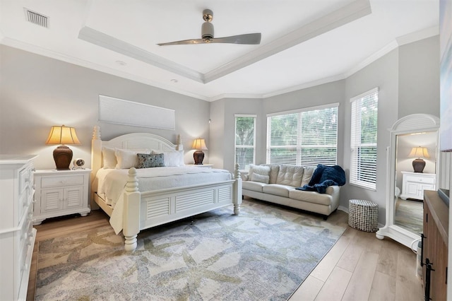 bedroom featuring a tray ceiling, ceiling fan, hardwood / wood-style floors, and ornamental molding