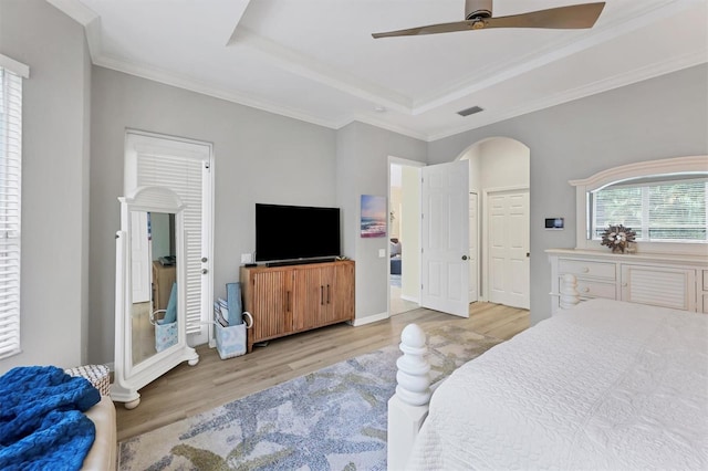 bedroom with a raised ceiling, ceiling fan, light hardwood / wood-style flooring, and ornamental molding