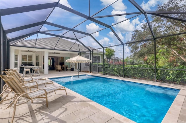 view of pool with glass enclosure, ceiling fan, and a patio area