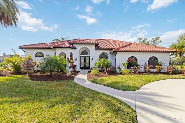 mediterranean / spanish-style house with a front lawn and french doors