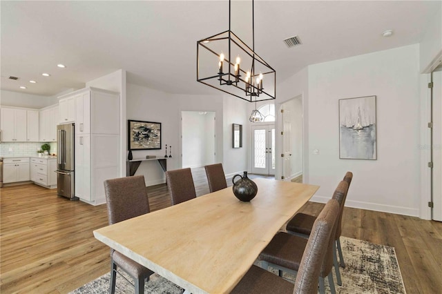 dining room with a chandelier, light wood-type flooring, and french doors