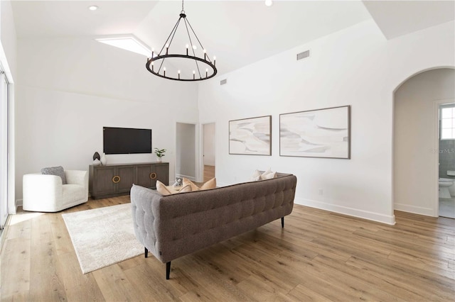 living room featuring light hardwood / wood-style flooring, high vaulted ceiling, and an inviting chandelier