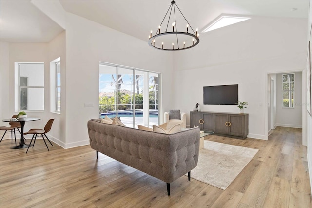 living room with a chandelier, light hardwood / wood-style flooring, high vaulted ceiling, and a healthy amount of sunlight