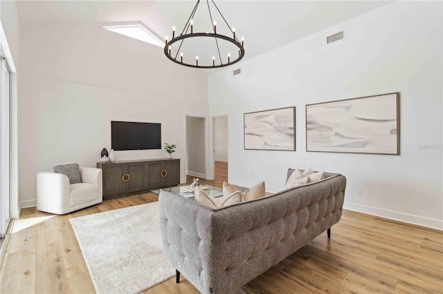 living room with light wood-type flooring, high vaulted ceiling, and a notable chandelier