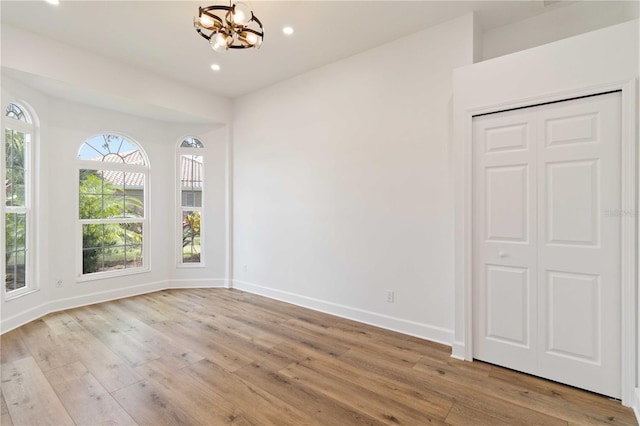 spare room featuring an inviting chandelier and light wood-type flooring