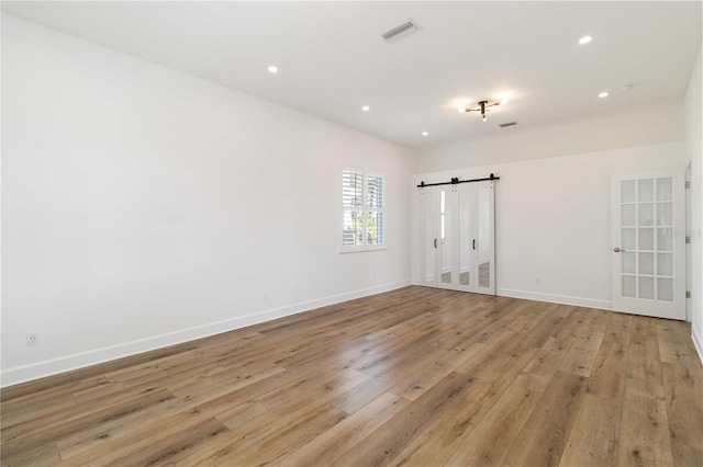 spare room featuring a barn door and light wood-type flooring