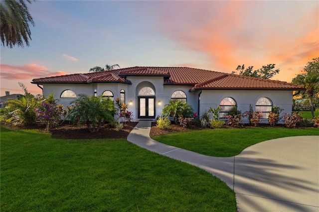 mediterranean / spanish home featuring a yard and french doors