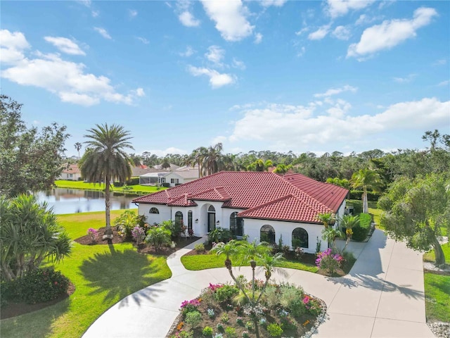 mediterranean / spanish-style home with a front lawn and a water view