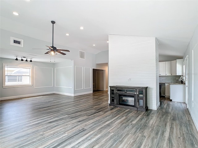 unfurnished living room featuring high vaulted ceiling, sink, hardwood / wood-style flooring, ceiling fan, and a fireplace